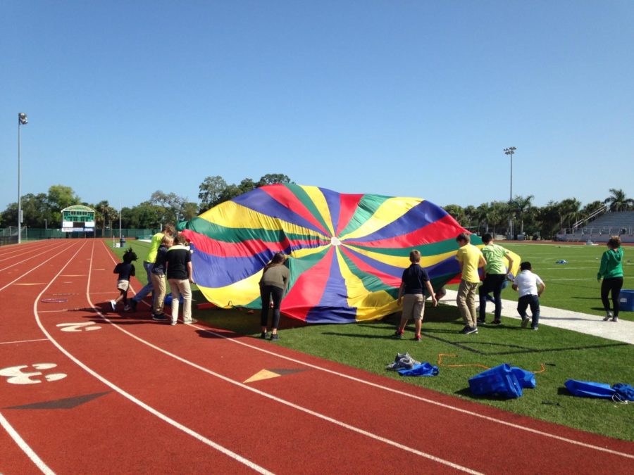 The kids let out some of their energy by playing with a parachute in the field.