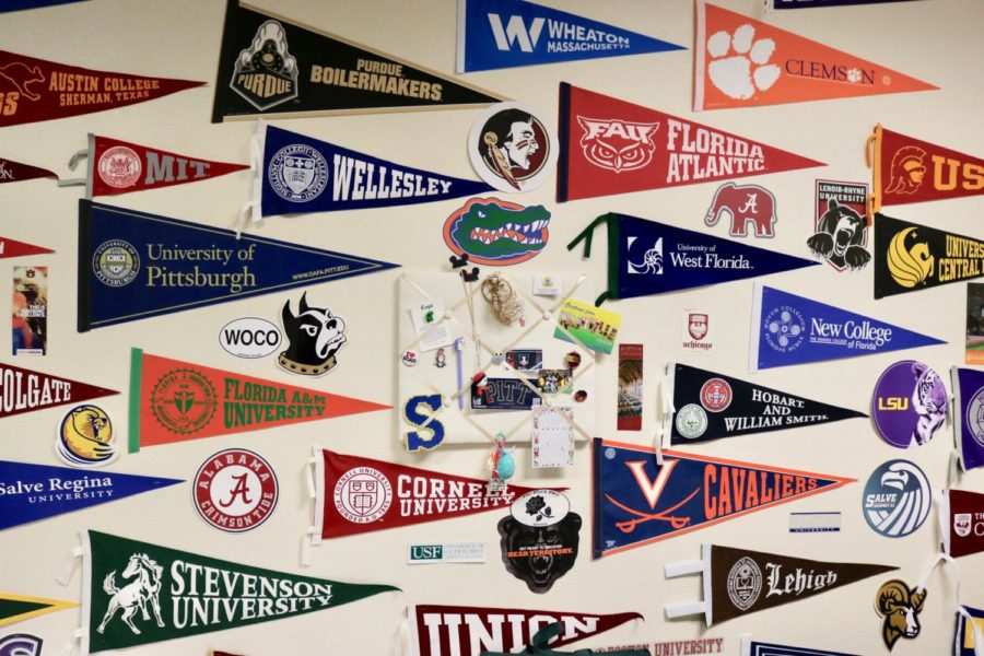 A collection of pennants from various universities is displayed on a wall of the college counseling office.