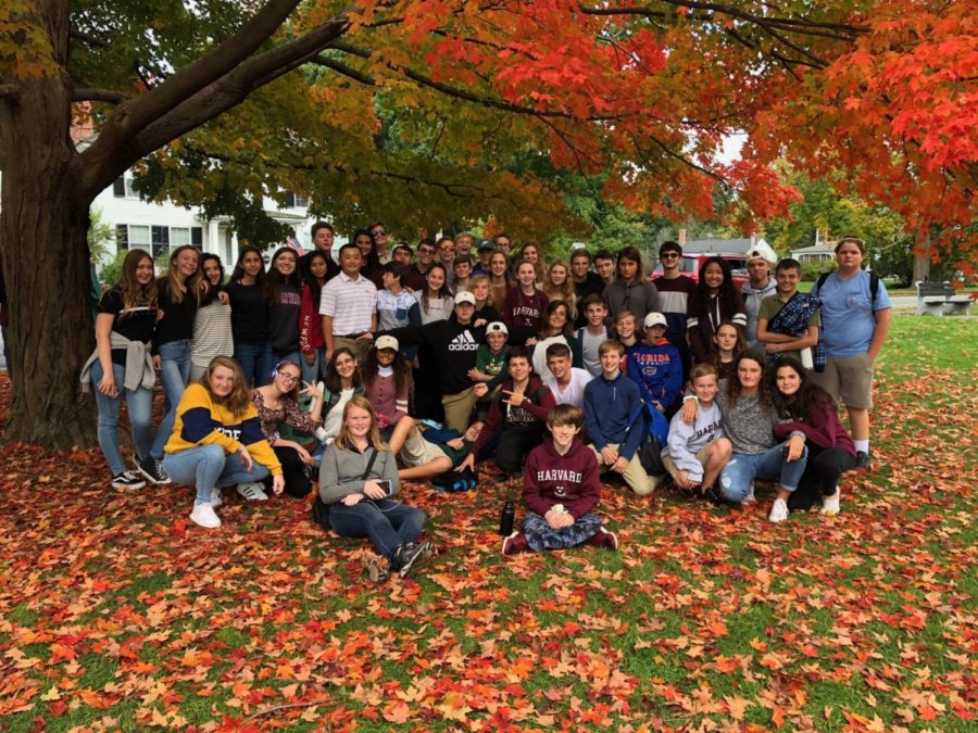 Eighth grade students gather among the leaves at Lexington Green for a group photo.