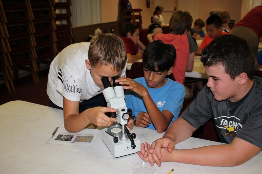 Mark Seklitov looks into the microscope for micro-plastics while Guy Dalzell helps adjust it so theyre visible.