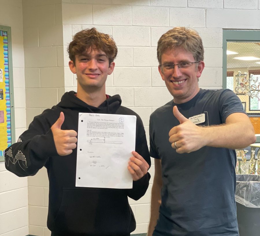High school Physics teacher Mr. Carlson poses with Danny Dodaj with holding a physics quiz.