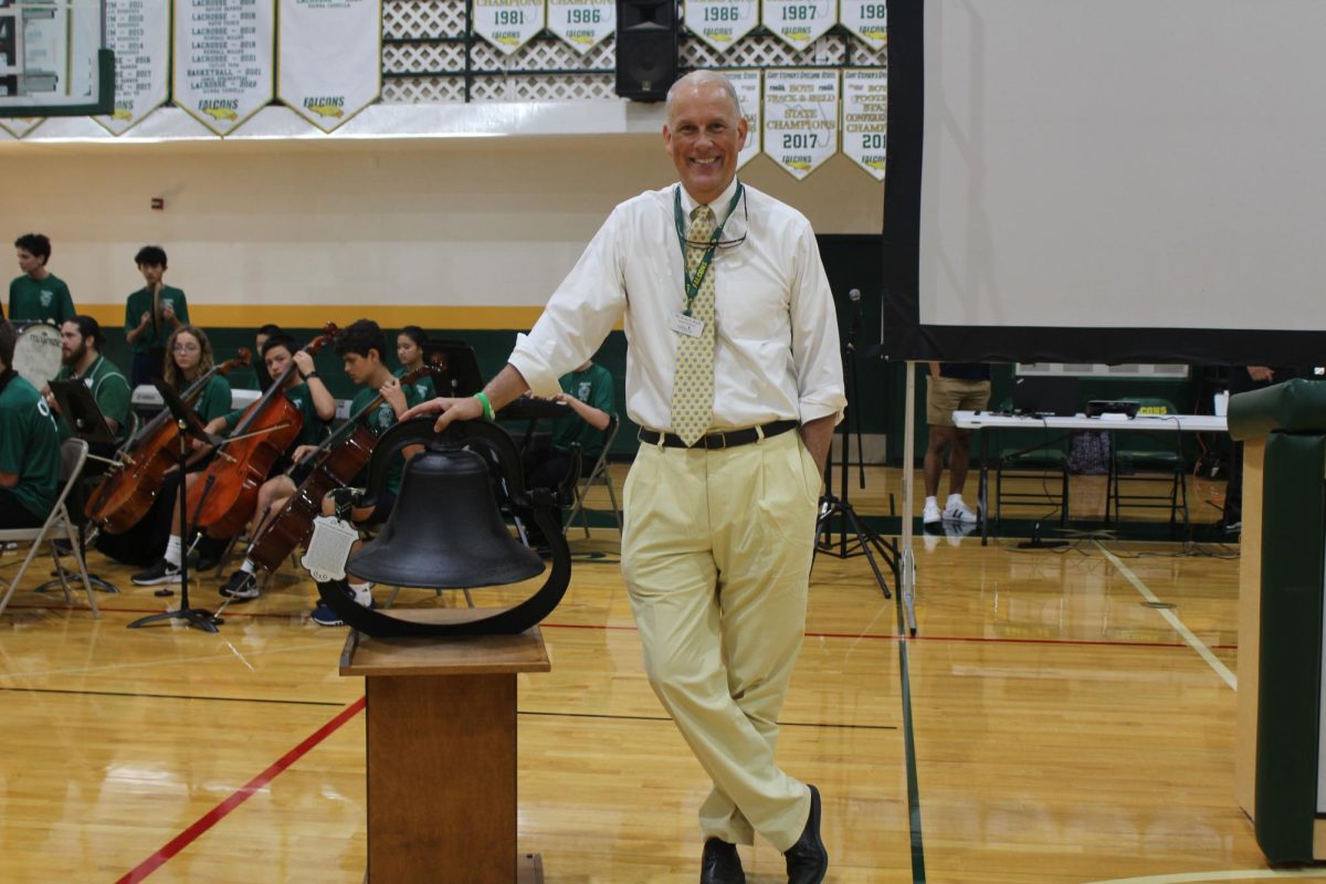 Head of School Mr. Kraft poses in front of the school bell. 