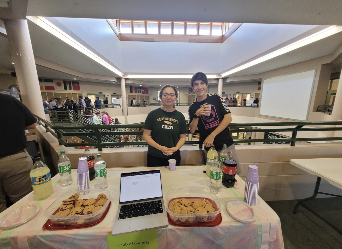 Seniors Sarabeth and Patrick pose next to the Club of the Arts stand. 