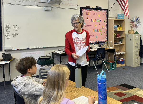 Fourth grade reading teacher Mrs. Ann Hunsader passes out Valentine's Day-themed papers to current students.